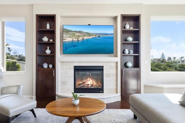 living area featuring built in features, a tile fireplace, and wood finished floors