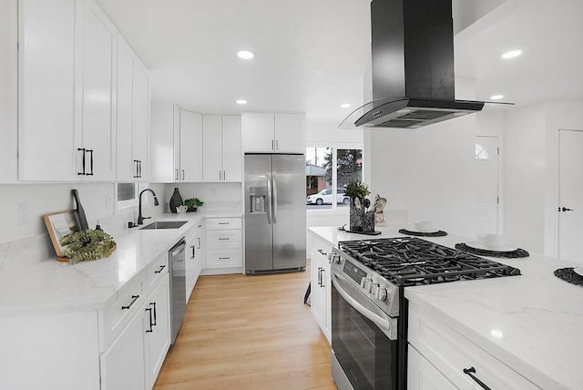 kitchen with island range hood, light stone countertops, stainless steel appliances, light wood-type flooring, and a sink