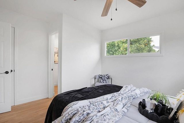 bedroom with ceiling fan, baseboards, and light wood-style floors