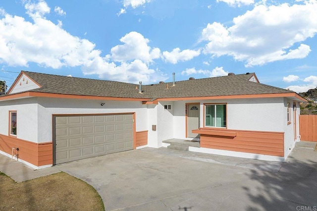 ranch-style house featuring roof with shingles, stucco siding, an attached garage, fence, and driveway