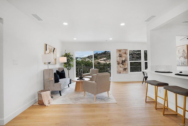 living area with recessed lighting, visible vents, baseboards, and wood finished floors