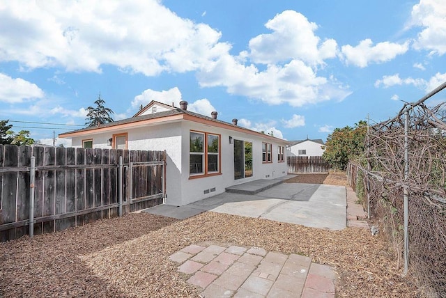 back of property with a fenced backyard, a patio, and stucco siding