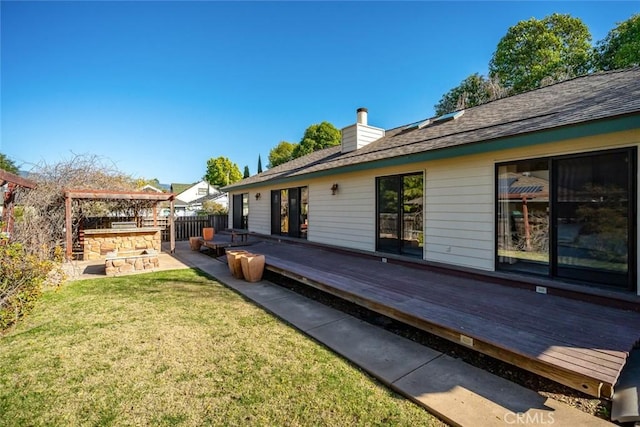 rear view of house with a yard, a chimney, fence, and a wooden deck