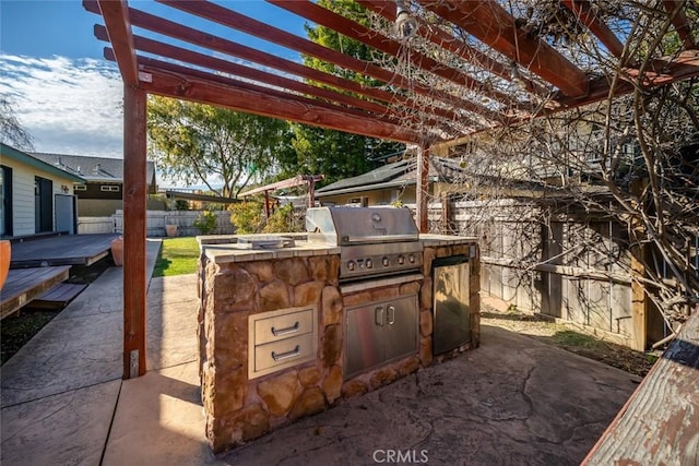 view of patio with exterior kitchen, a fenced backyard, grilling area, and a pergola