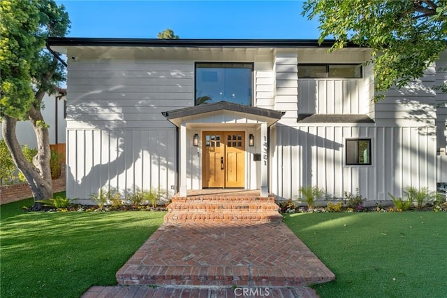 view of front facade with a front lawn and board and batten siding