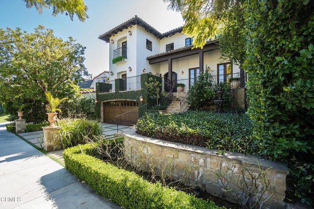 view of property exterior with a tiled roof, stairway, a garage, and stucco siding