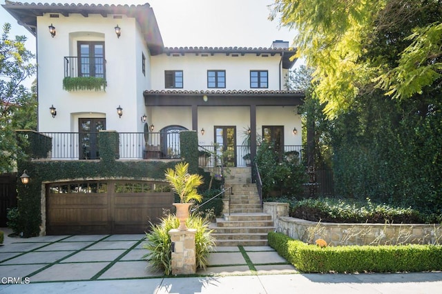 mediterranean / spanish-style home with an attached garage, concrete driveway, a tile roof, stairway, and stucco siding