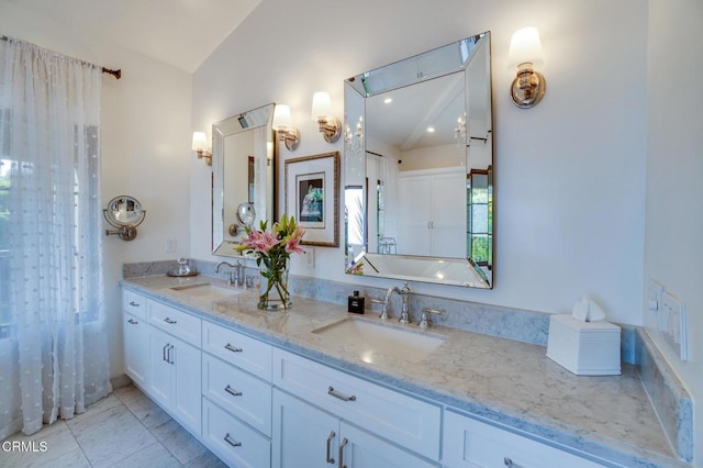bathroom with a sink, double vanity, and lofted ceiling