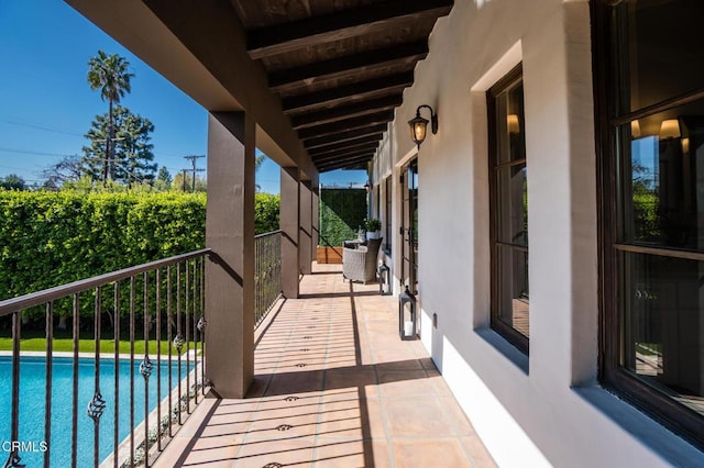 view of patio featuring an outdoor pool and a balcony