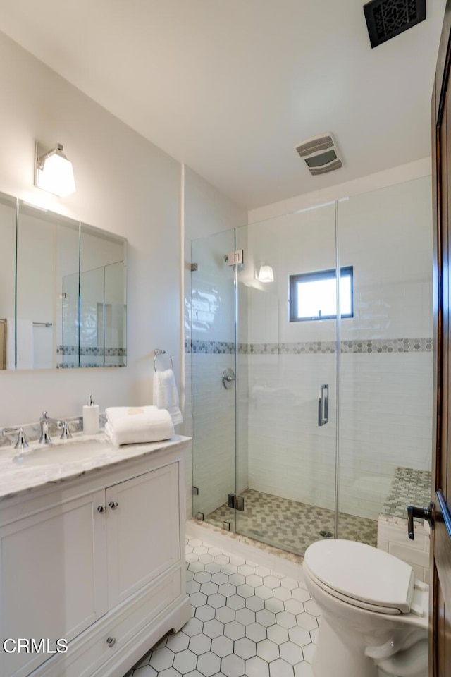 bathroom featuring toilet, a stall shower, vanity, and visible vents