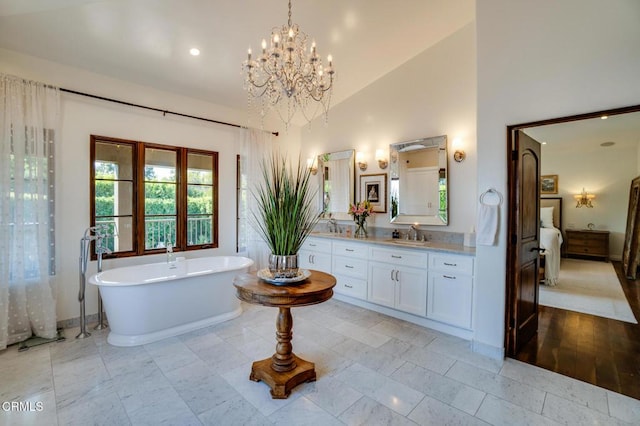 ensuite bathroom featuring a soaking tub, high vaulted ceiling, vanity, ensuite bath, and a notable chandelier