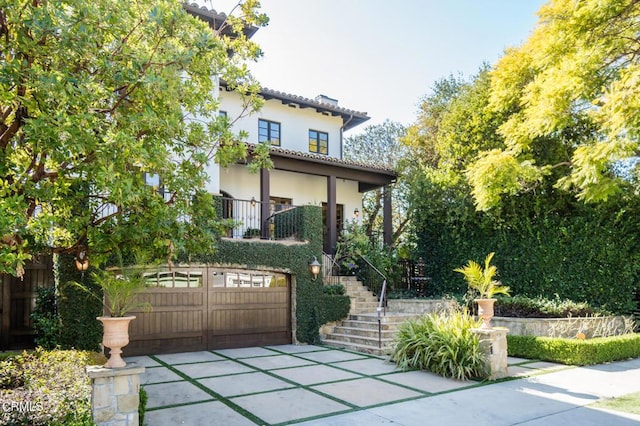 view of front of property with fence, stairway, an attached garage, and stucco siding