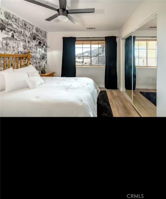 bedroom with light wood-type flooring, baseboards, multiple windows, and visible vents