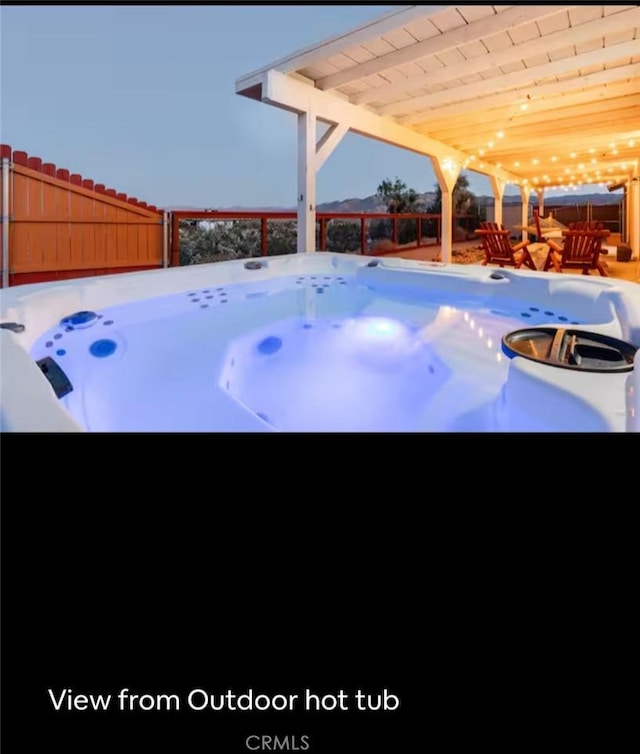 snow covered patio with fence and a hot tub