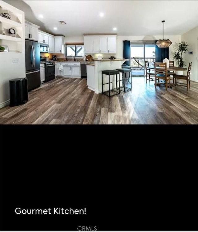 kitchen featuring a breakfast bar area, open shelves, white cabinetry, black appliances, and decorative light fixtures