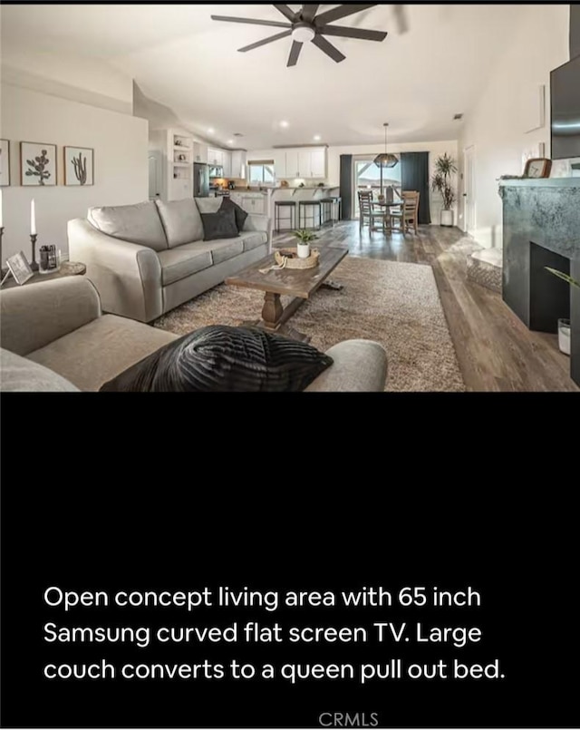 living room featuring lofted ceiling, a fireplace, a ceiling fan, and wood finished floors