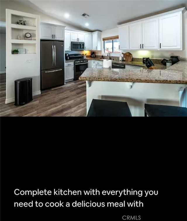 kitchen with a peninsula, white cabinetry, stainless steel appliances, and lofted ceiling