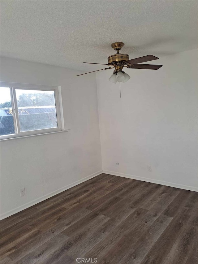 empty room with a textured ceiling, dark wood-style flooring, a ceiling fan, and baseboards