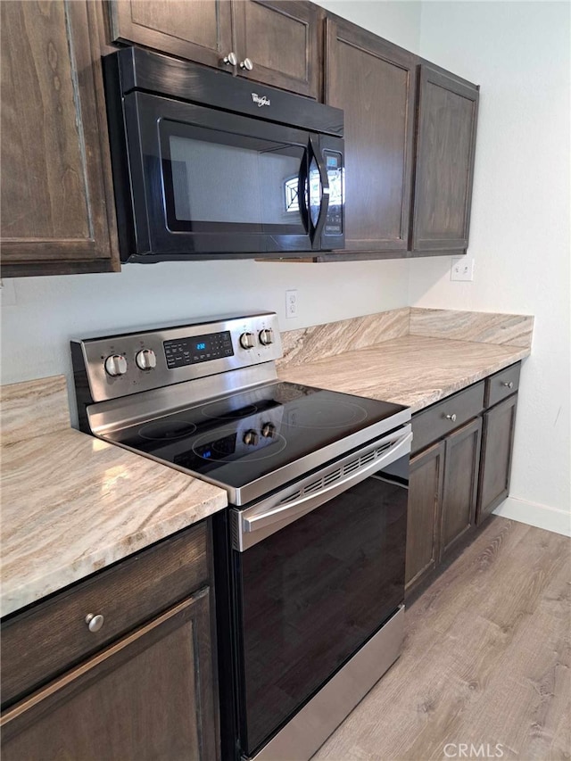 kitchen featuring black microwave, light countertops, dark brown cabinets, and stainless steel range with electric cooktop