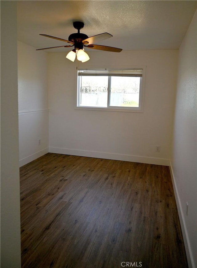 spare room featuring a textured ceiling, ceiling fan, dark wood-style flooring, and baseboards