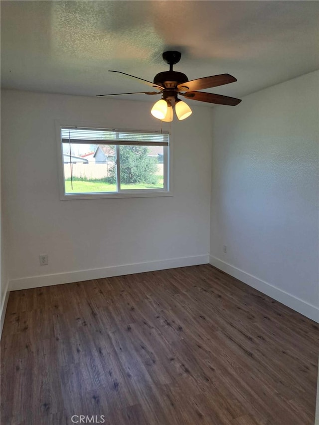 spare room featuring dark wood-type flooring, a textured ceiling, baseboards, and a ceiling fan