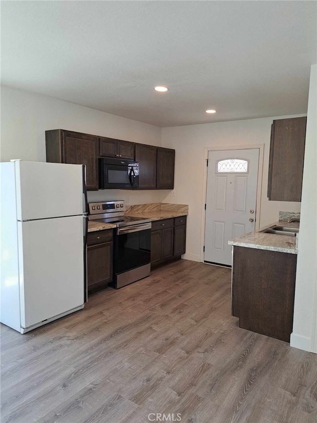 kitchen with light wood finished floors, freestanding refrigerator, stainless steel electric range, light countertops, and black microwave