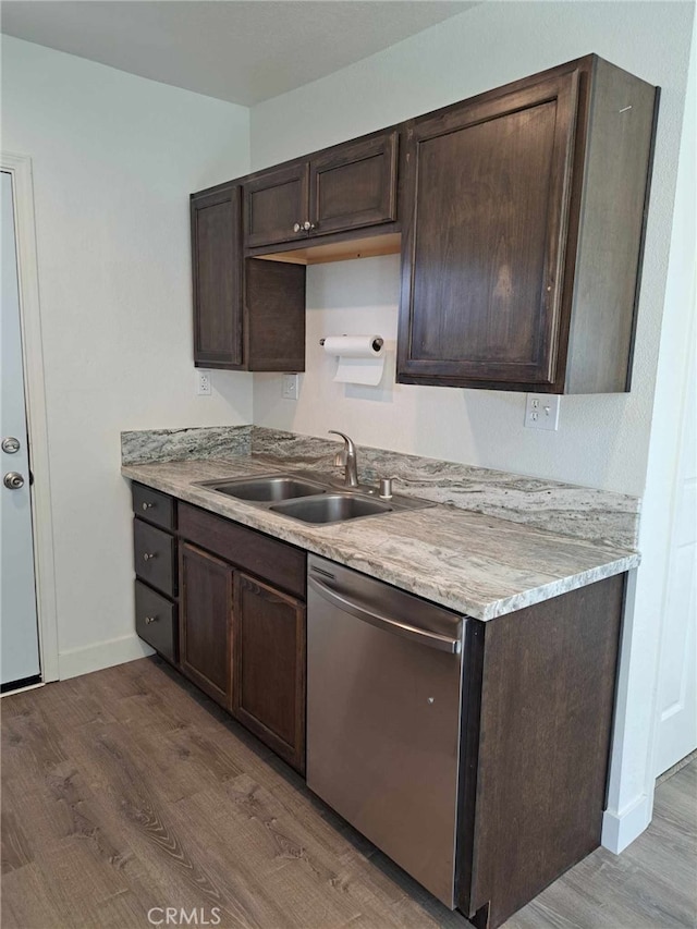 kitchen with dark brown cabinetry, baseboards, dishwasher, light wood-style floors, and a sink