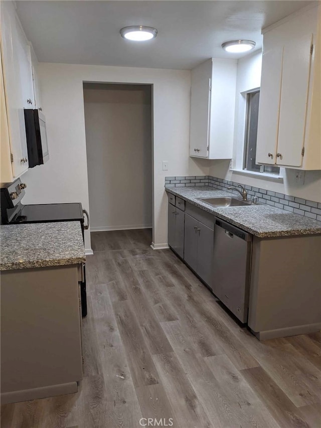 kitchen featuring light stone counters, white cabinetry, a sink, black microwave, and dishwasher