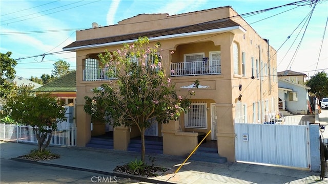 view of front of property featuring a fenced front yard, a balcony, and stucco siding