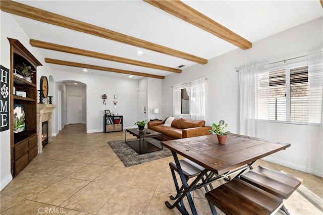 dining area with light tile patterned floors, baseboards, arched walkways, and beam ceiling