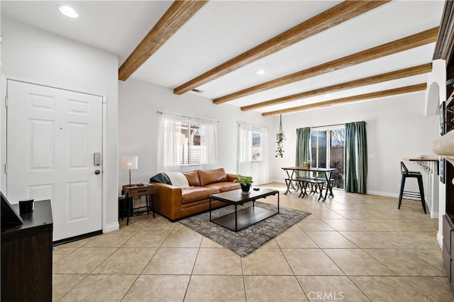 living room with light tile patterned floors, beamed ceiling, and baseboards