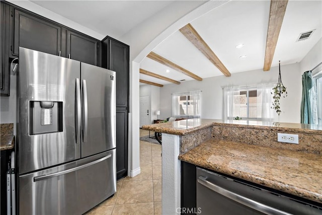 kitchen featuring light tile patterned floors, stone countertops, arched walkways, appliances with stainless steel finishes, and beamed ceiling