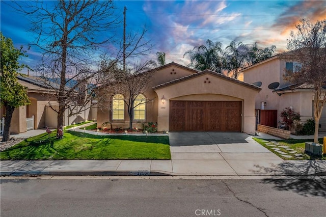 mediterranean / spanish home featuring driveway, a garage, a tile roof, a yard, and stucco siding