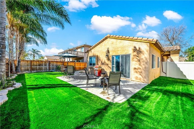 back of house with stucco siding, a fenced backyard, a patio, and a yard