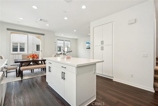 kitchen featuring a center island, dark wood-style flooring, light countertops, visible vents, and white cabinets