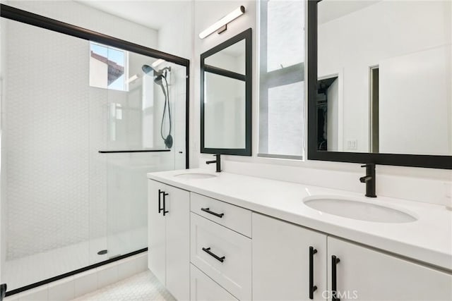 full bath with double vanity, a stall shower, and a sink