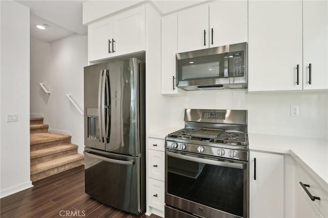 kitchen with stainless steel appliances, light countertops, dark wood-type flooring, white cabinets, and baseboards