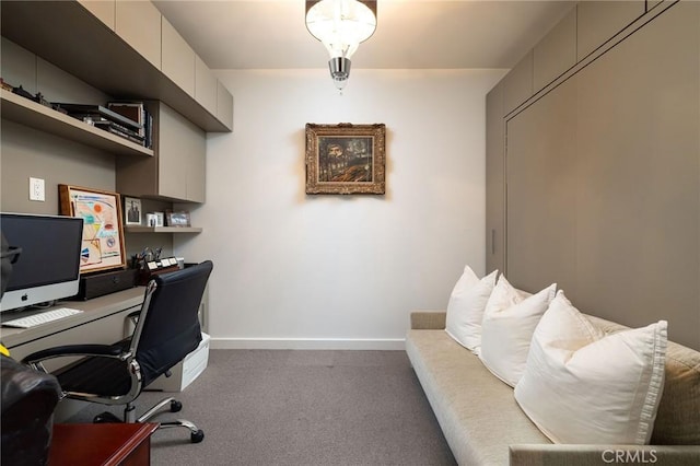 home office with dark colored carpet and baseboards