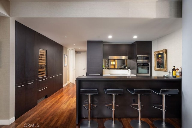 kitchen featuring a peninsula, appliances with stainless steel finishes, modern cabinets, and a kitchen bar