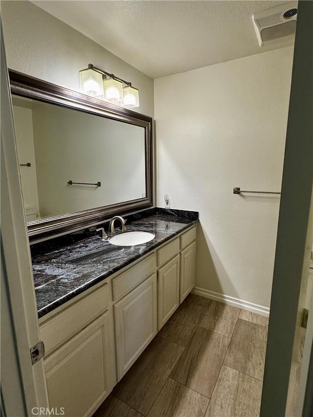 bathroom with baseboards, visible vents, vanity, a textured ceiling, and wood finish floors