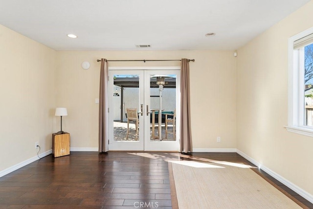 unfurnished room with plenty of natural light, visible vents, dark wood finished floors, and french doors