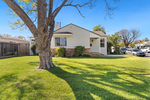 view of front of home featuring a chimney, stucco siding, fence, stone siding, and a front lawn