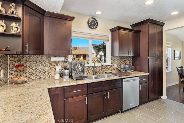 kitchen featuring light stone counters, open shelves, tasteful backsplash, stainless steel dishwasher, and a sink