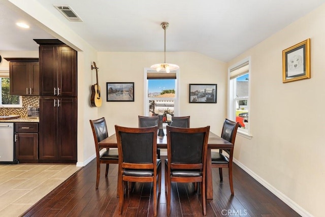 dining room with a notable chandelier, baseboards, visible vents, and wood finished floors