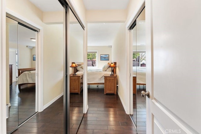 hallway featuring dark wood finished floors and baseboards