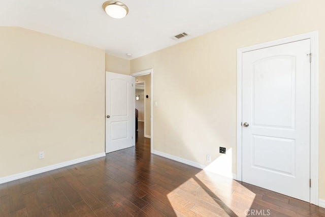 unfurnished room with dark wood finished floors, visible vents, and baseboards