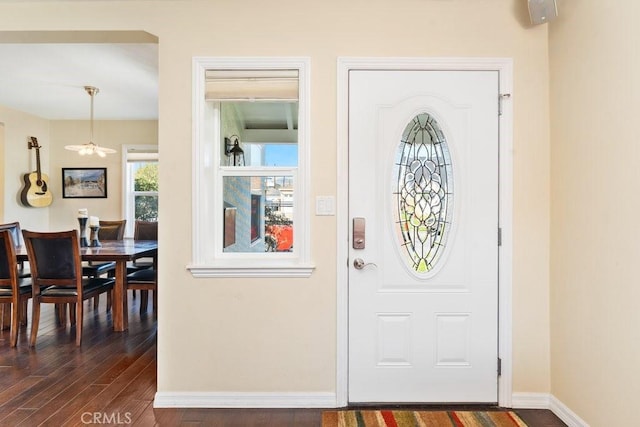 foyer entrance with dark wood finished floors and baseboards