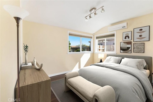 bedroom with lofted ceiling, a wall unit AC, baseboards, dark wood-style floors, and rail lighting