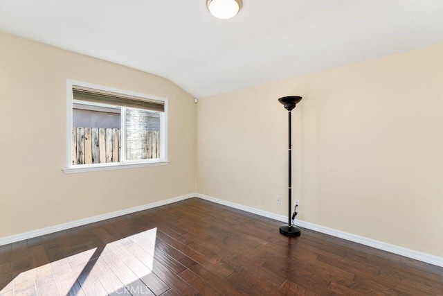 spare room with dark wood-style floors, lofted ceiling, and baseboards