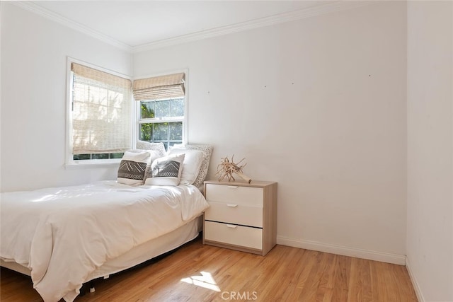 bedroom with light wood finished floors, baseboards, and crown molding